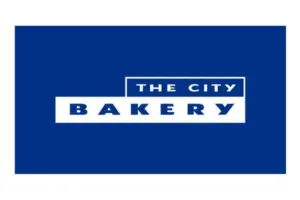 Logo for The City Bakery featuring white text on blue with stacked ribbons reading THE CITY and BAKERY