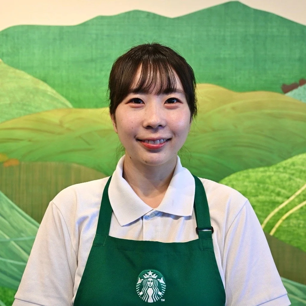 スターバックスのエプロンを着用し笑顔の女性バリスタ