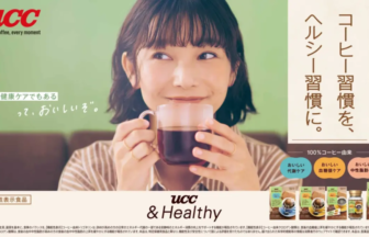 Woman smiles while holding a cup of coffee in a green themed UCC advertisement with product packs at the bottom