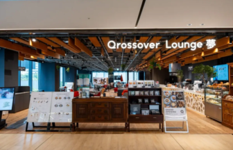 Interior of a cafe called Qrossover Lounge, featuring wooden ceiling beams, a long wooden counter, and pastry display cases.