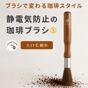 Japanese ad for a coffee brush that prevents static a wooden handled brush with a metal ferrule stands upright on a surface with coffee grounds with bold Japanese text and a brown button reading 人口毛硬め