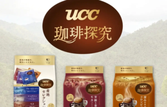 Poster advertising UCC coffee with three coffee bags and the slogan '産地に出会い、コーヒーの魅力を知る' above the UCC 珈琲探究 logo.