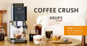 Krups Coffee Crush espresso machine on a wooden table with cups and a carafe orange tag with Japanese text on the right