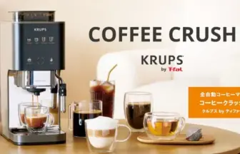 Krups Coffee Crush espresso machine on a wooden table with cups and a carafe orange tag with Japanese text on the right