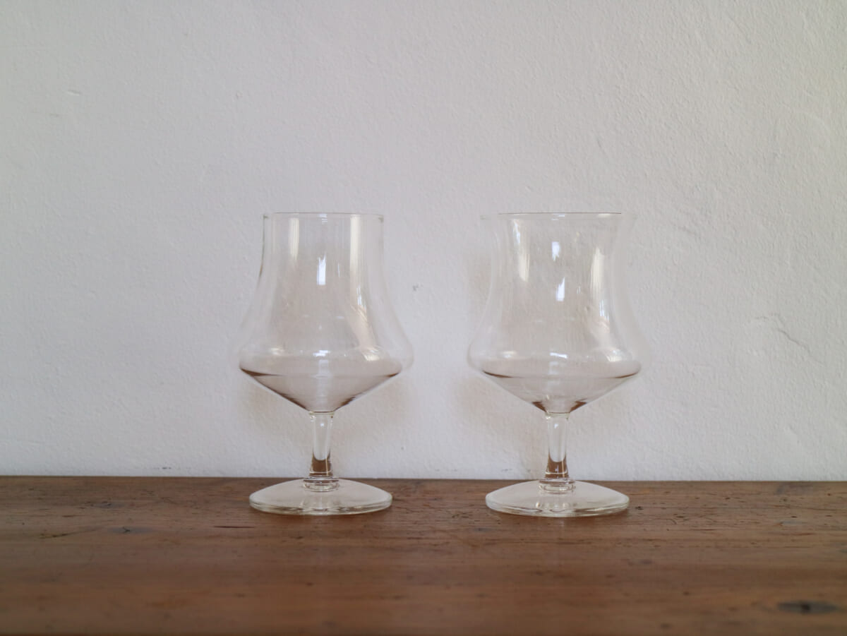 IMG4229 | コーヒーステーション Two empty whiskey snifter glasses resting on a wooden table against a pale wall