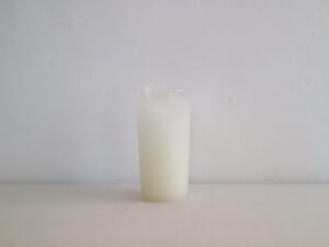Tall glass of milk on a white surface against a pale gray wall