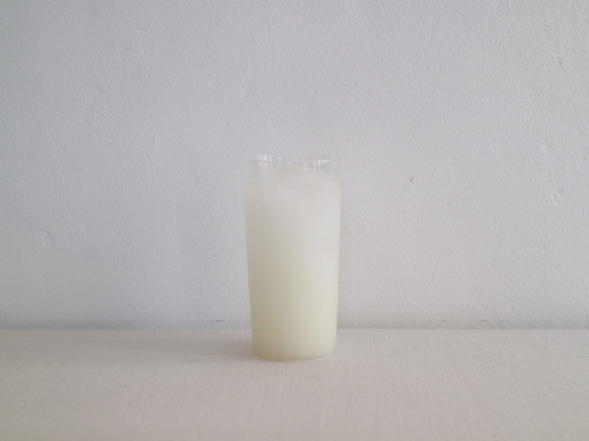 Tall glass of milk on a white surface against a pale gray wall
