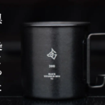 Black titanium mug with a geometric logo on the front and vertical Japanese text along the left edge
