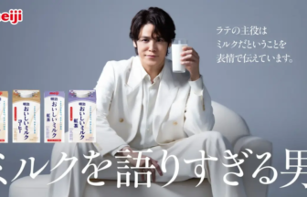 Meiji advertisement showing a man in a white suit sitting on a white sofa, holding a glass of milk, with four Meiji milk cartons on the left and a bold Japanese slogan across the bottom.
