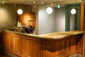 Wooden curved bar with marble top espresso machine grinder and cups in a cozy cafe setting