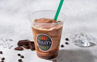 Chocolate frappé in a clear cup with a green straw and Tullys Coffee logo on a gray surface