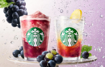 Two Starbucks drinks on a glass pedestal with grape clusters one pink slushy and one citrus against a purple background