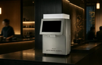 Automated drink dispenser labeled 'Auto Drink Barista' on a polished bar counter in a dimly lit lounge.
