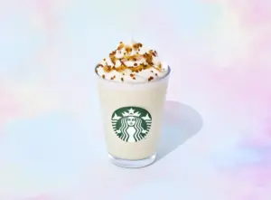 Starbucks frappuccino in a clear cup topped with whipped cream and caramel drizzle against a pastel background