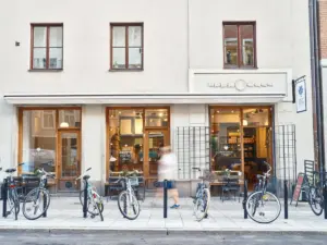 Café storefront with large glass doors and windows bicycles parked along the sidewalk and a blurred pedestrian walking by