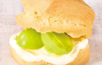 Soft sandwich bun filled with cream cheese and two green grapes inside the bun.