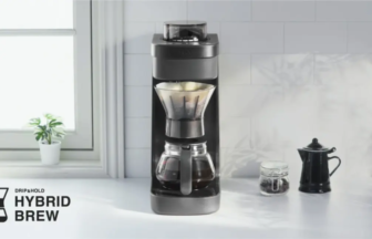 Black drip coffee machine with glass carafe on a white kitchen counter Hybrid Brew branding visible in the lower left corner