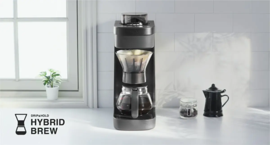 Black drip coffee machine with glass carafe on a white kitchen counter Hybrid Brew branding visible in the lower left corner