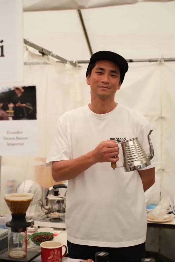 コーヒーケトルを手に笑顔で立つ男性