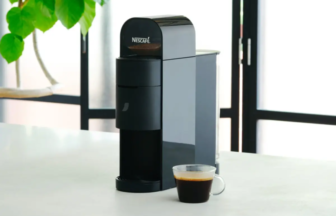 Nescafé coffee machine on a white countertop with a cup of coffee beside it