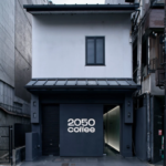 Two story white building with a dark storefront reading 2050 coffee on a city street