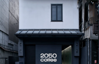 Two story white building with a dark storefront reading 2050 coffee on a city street