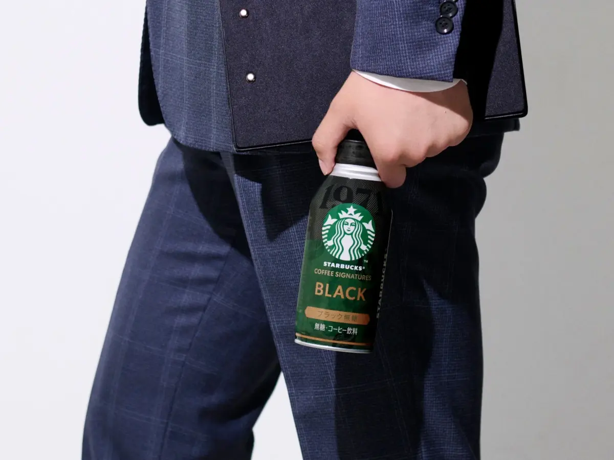スターバックス® COFFEE SIGNATURES BLACKのボトル缶を持つビジネスパーソン